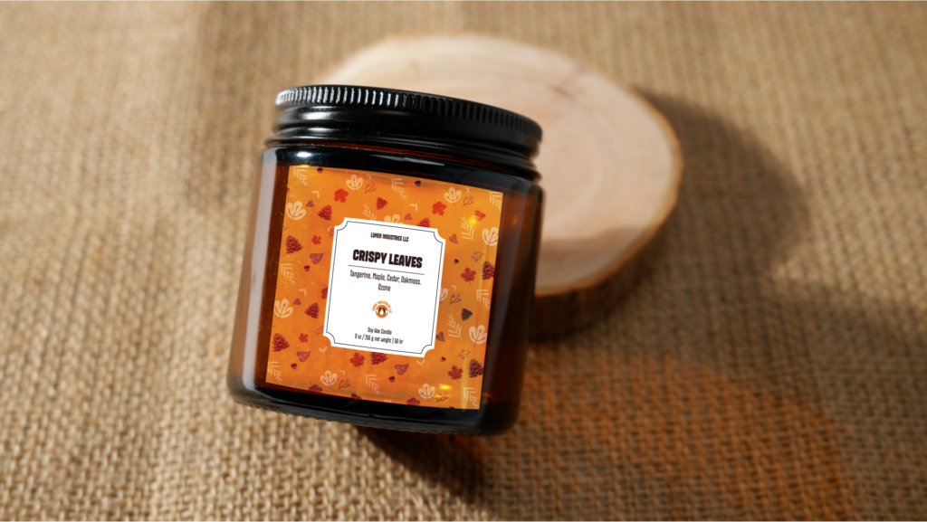 Cozy Autumn Candles, crispy leaves candle label with orange leaf pattern mock-up on an amber candle container.